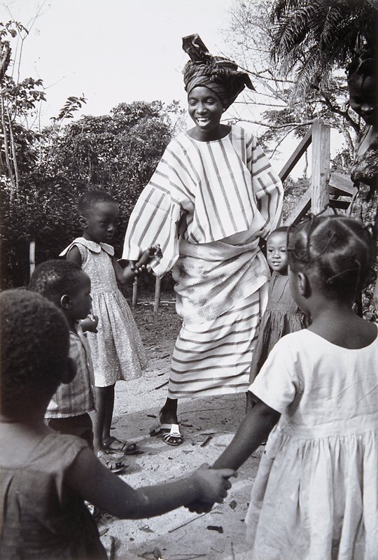 Nigeria, Modern King: Wife no. 1 of the King of Akure, Mrs. Adesida plays with little girls at a kindergarten she helped organize for children of working mothers in Akure., Marc Bernheim, 20th century