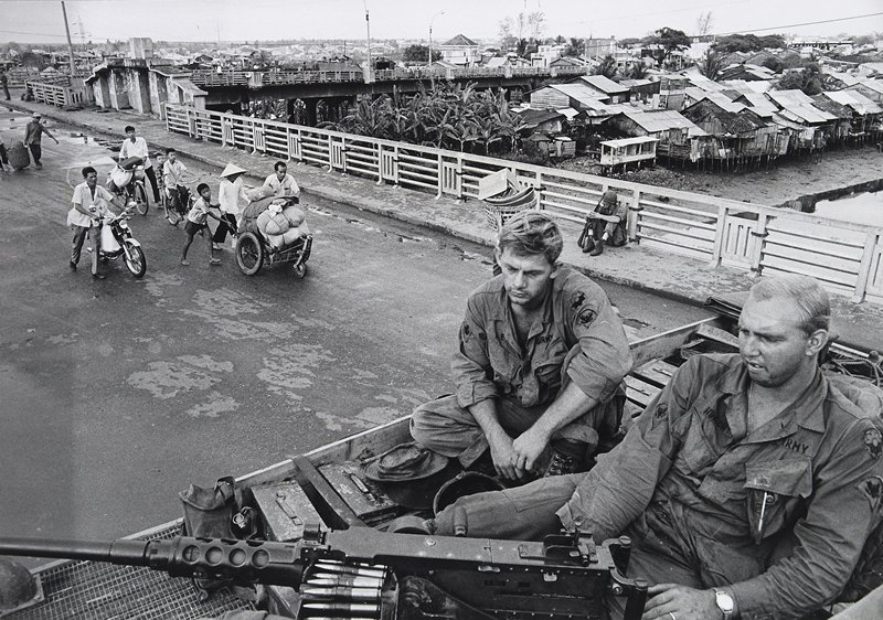 Saigon Under Attack: American soldiers sitting on top of an armored personnel carrier guarding one portion of the Y Bridge while civilians flee from the other side into the center of Saigon, Philip Jones Griffiths, 20th-21st century