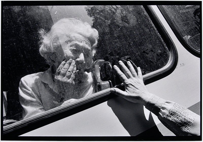Untitled (older woman sitting in bus window, hand held outside touching window), Gilles Peress, 1993