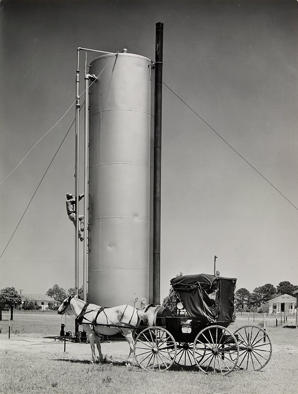 Oil Field, Tomball, Texas. James Tanner, pumper, climbing heater-treater to check water and oil level in gauge glass.  Because of the gasoline shortage, he uses horse and buggy to make his daily rounds., Esther Bubley, 1945