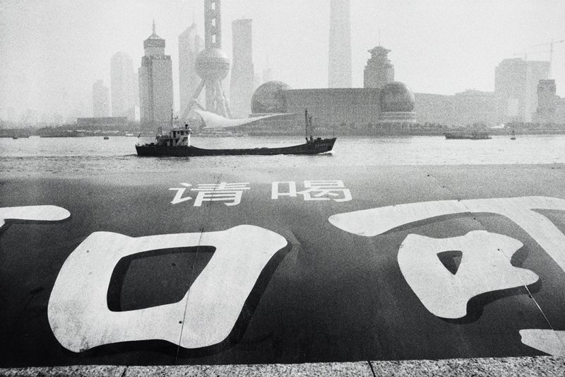 In Background, Pudong, the new Shanghai with a Coca-Cola ad in foreground, Marc Riboud, 2002