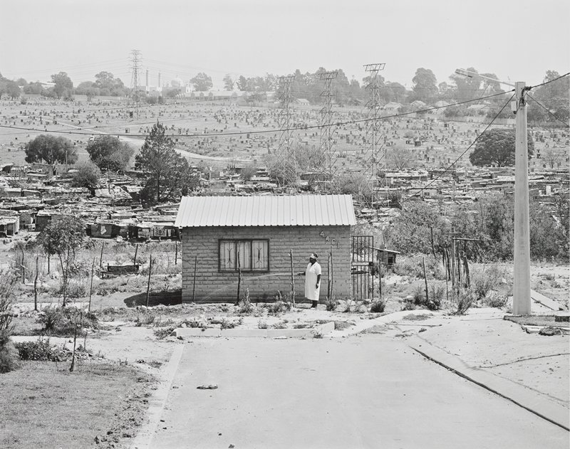 Miriam Mazibuko waters the garden of her RDP house for which she waited eight years. It consists of one room. Her four children live with her in-laws. Extension 8, Far East Alexandra Township by David Goldblatt