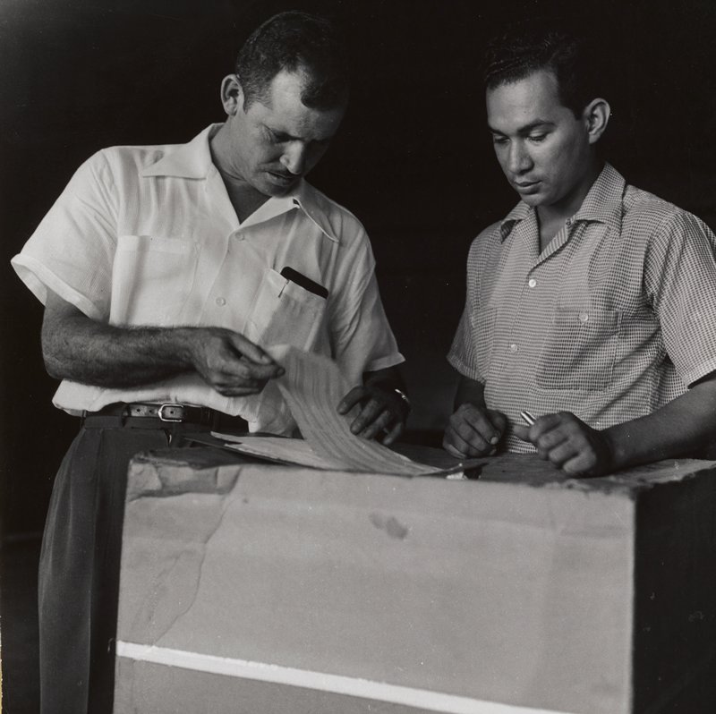 Jose looking over papers with worker, Puerto Rico, Jacques Lowe, 1954