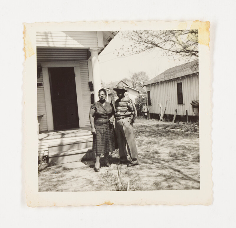[Couple standing in yard beside house], c. 1950
