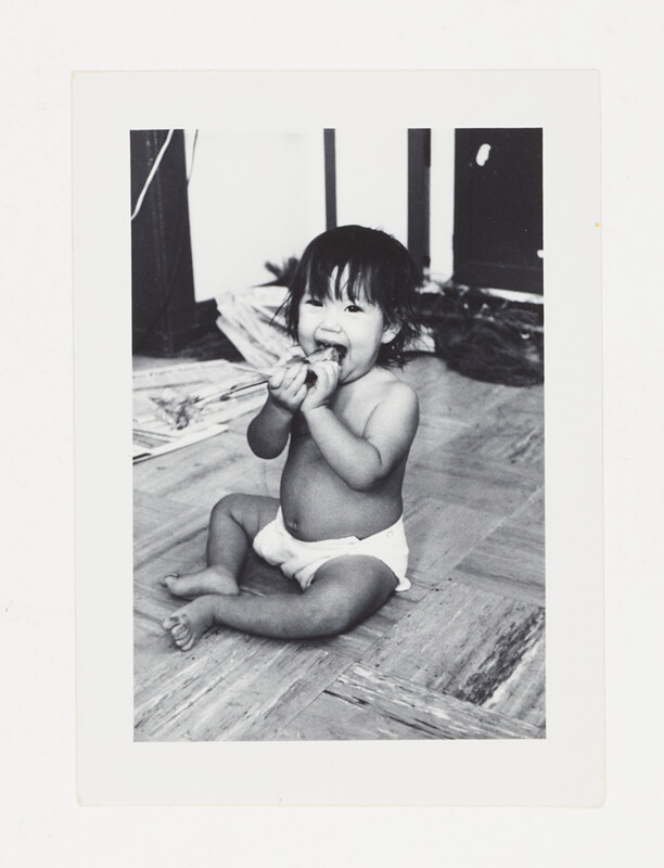 [Toddler eating while seated on floor], c. 1975
