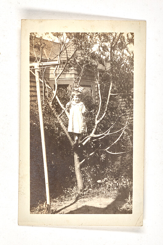 [Girl standing in backyard tree], 1920–30