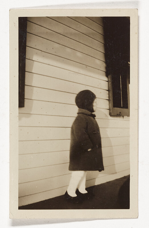[Child standing by clapboard wall], 1940s–50s