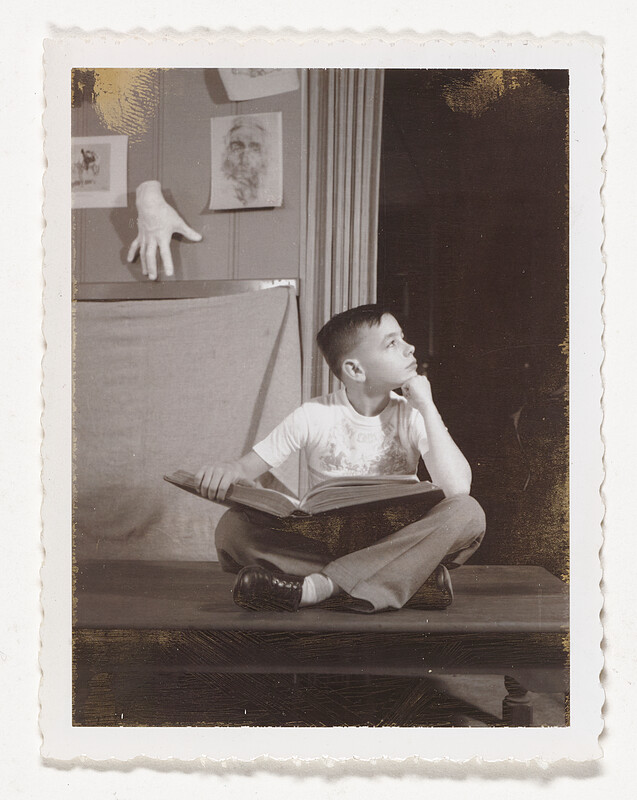 [Boy sitting cross-legged with open book], c. 1950